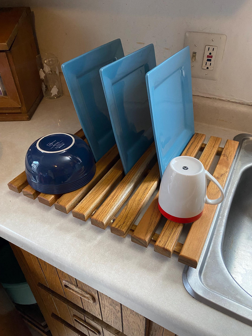 Teak dish drying rack holding plates, bowls and a cup