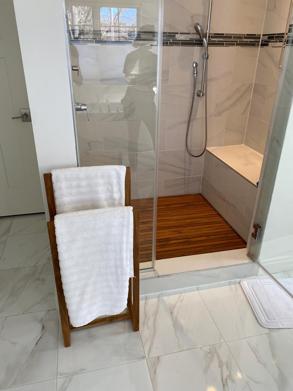 Solid teak towel rack mounted on a bathroom wall with towels