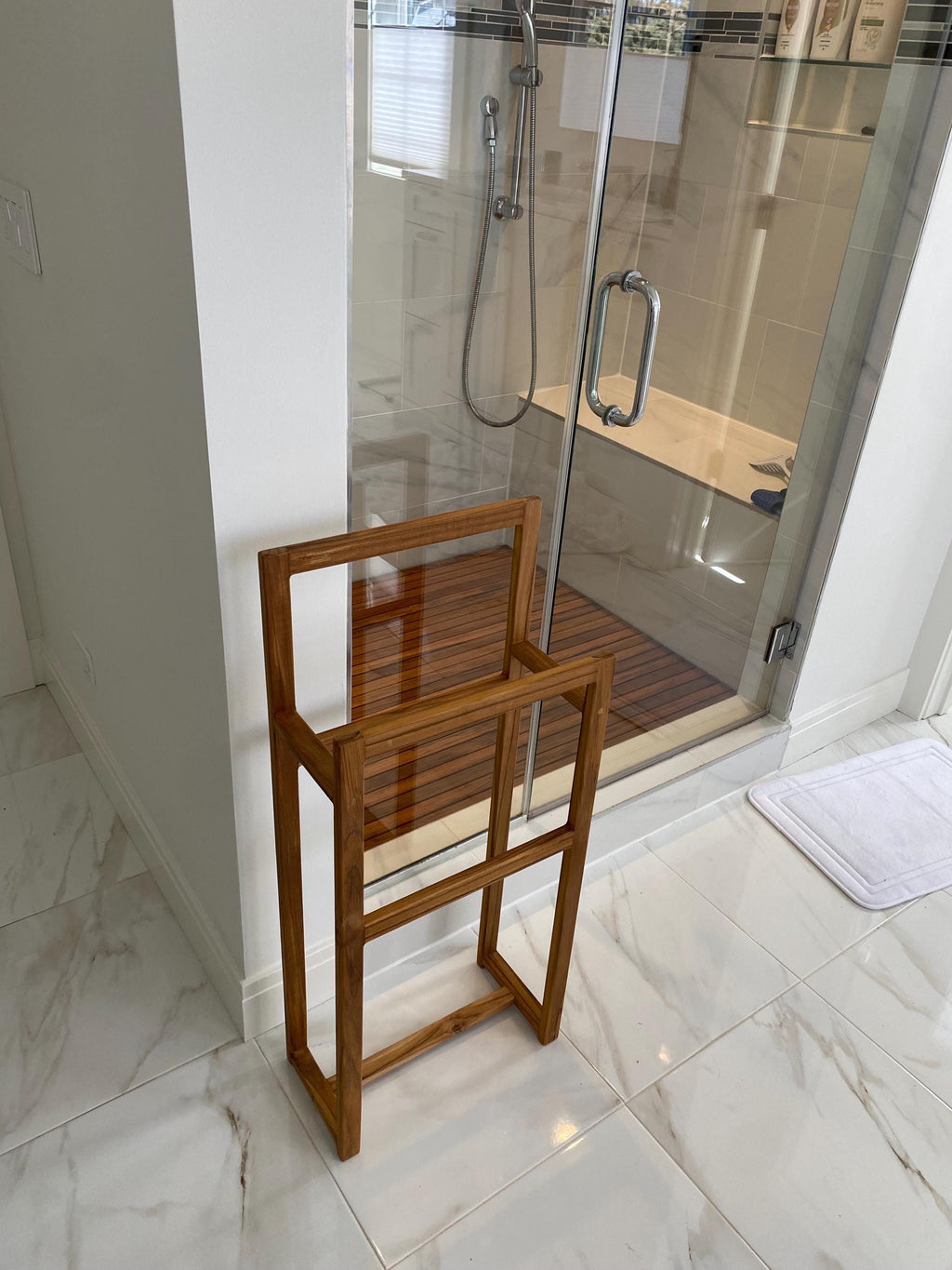 Solid teak towel rack mounted on a bathroom wall above