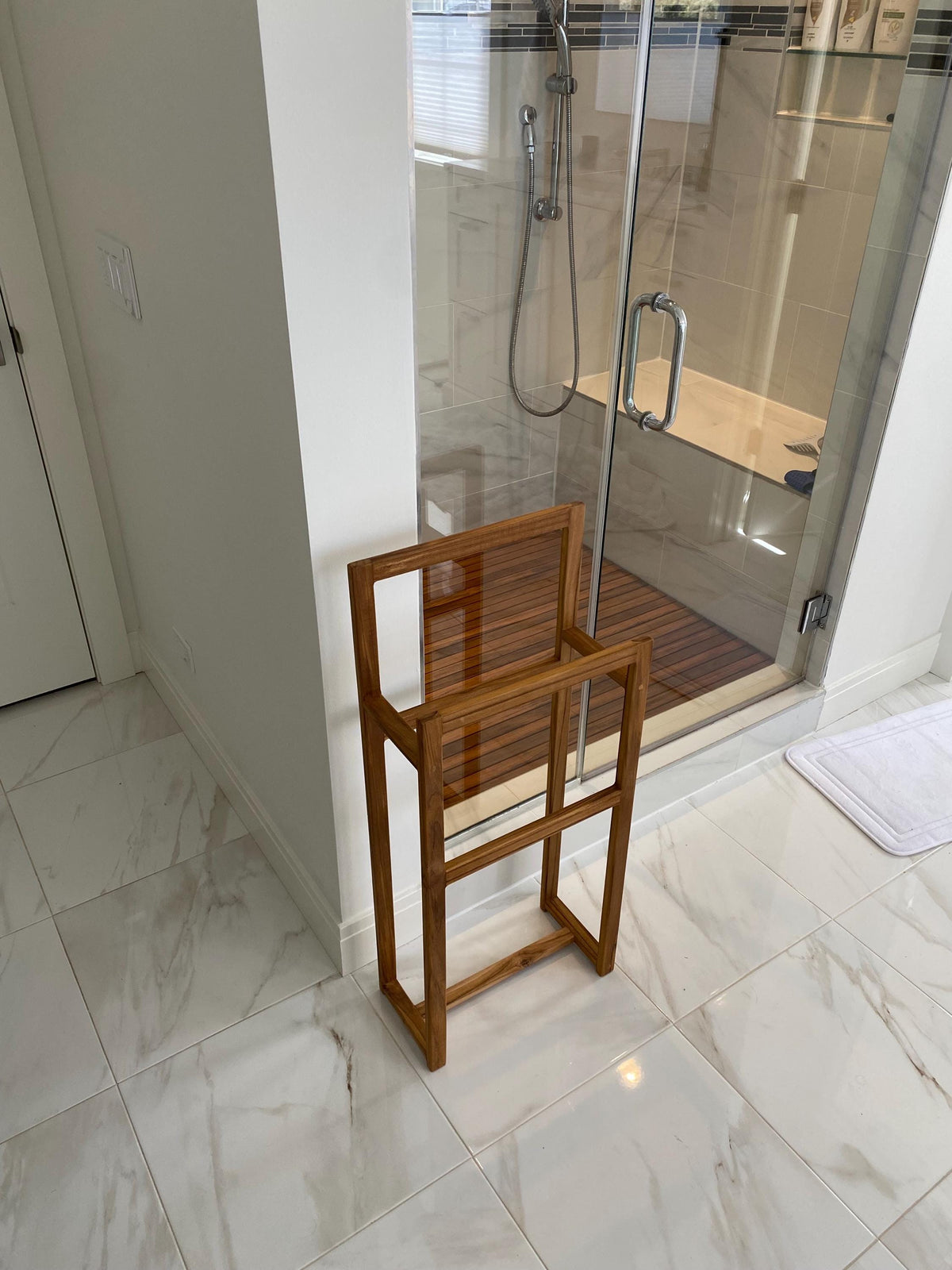 Solid teak towel rack mounted on a bathroom wall empty