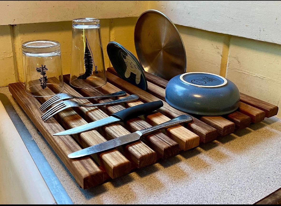 Teak dish drying rack holding plates and cups in a kitchen