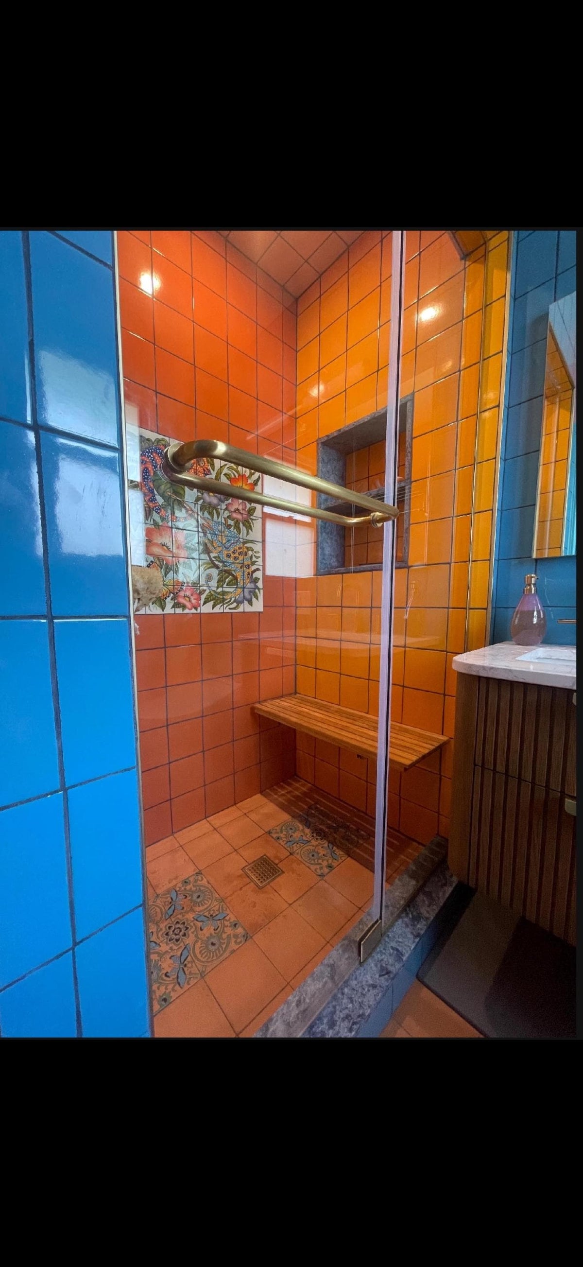 Wall-mounted teak folding shower bench in the down position