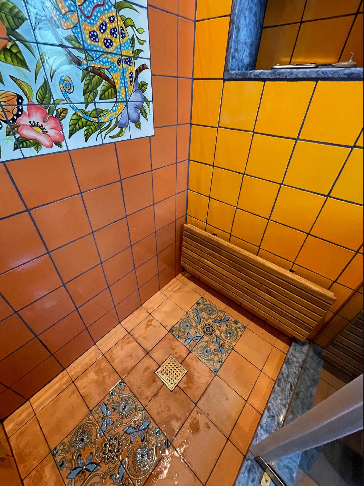Wall-mounted teak folding shower bench in the up position