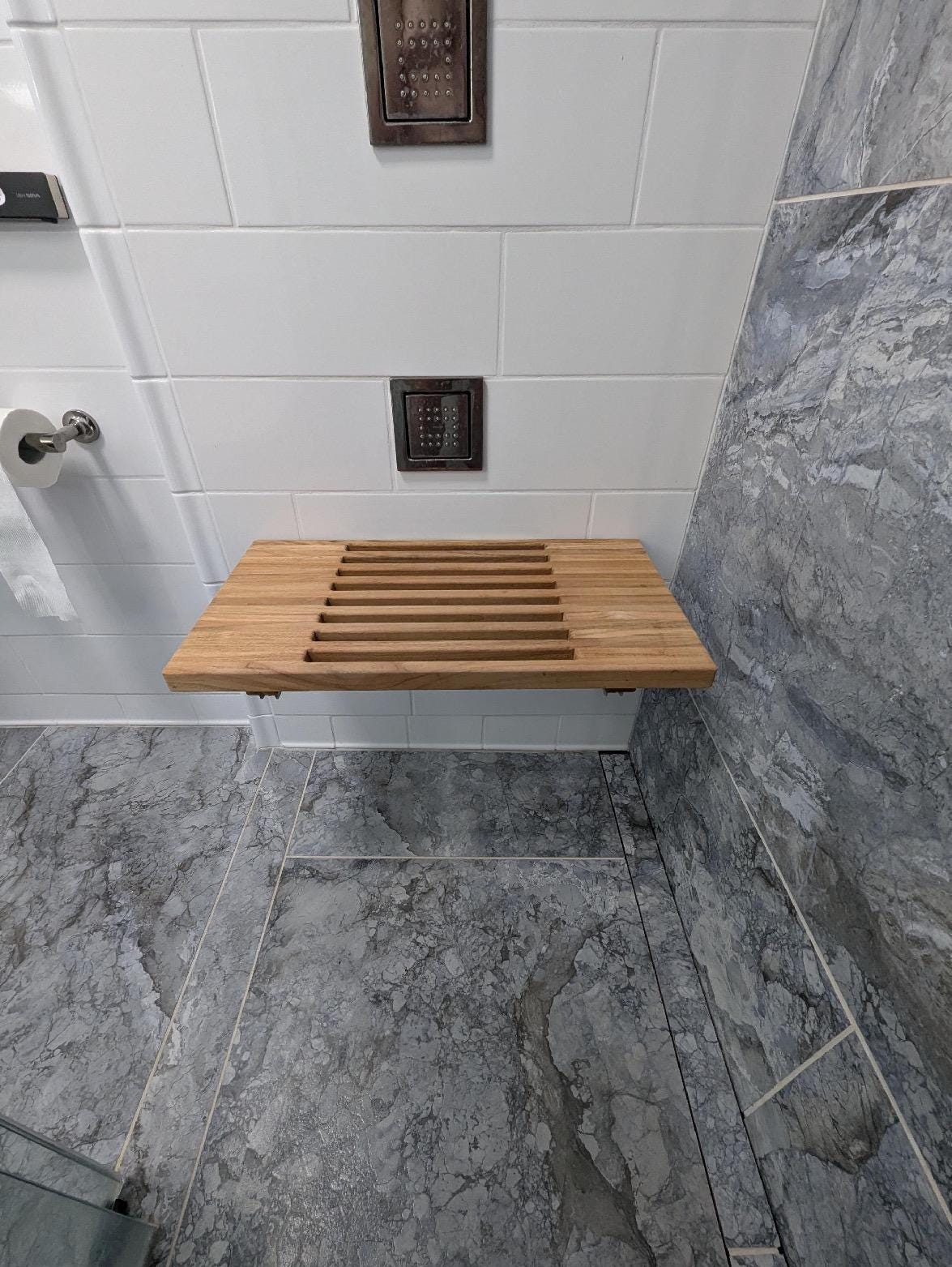 Slatted teak wall-mount bench with drainage gaps between boards folded down
