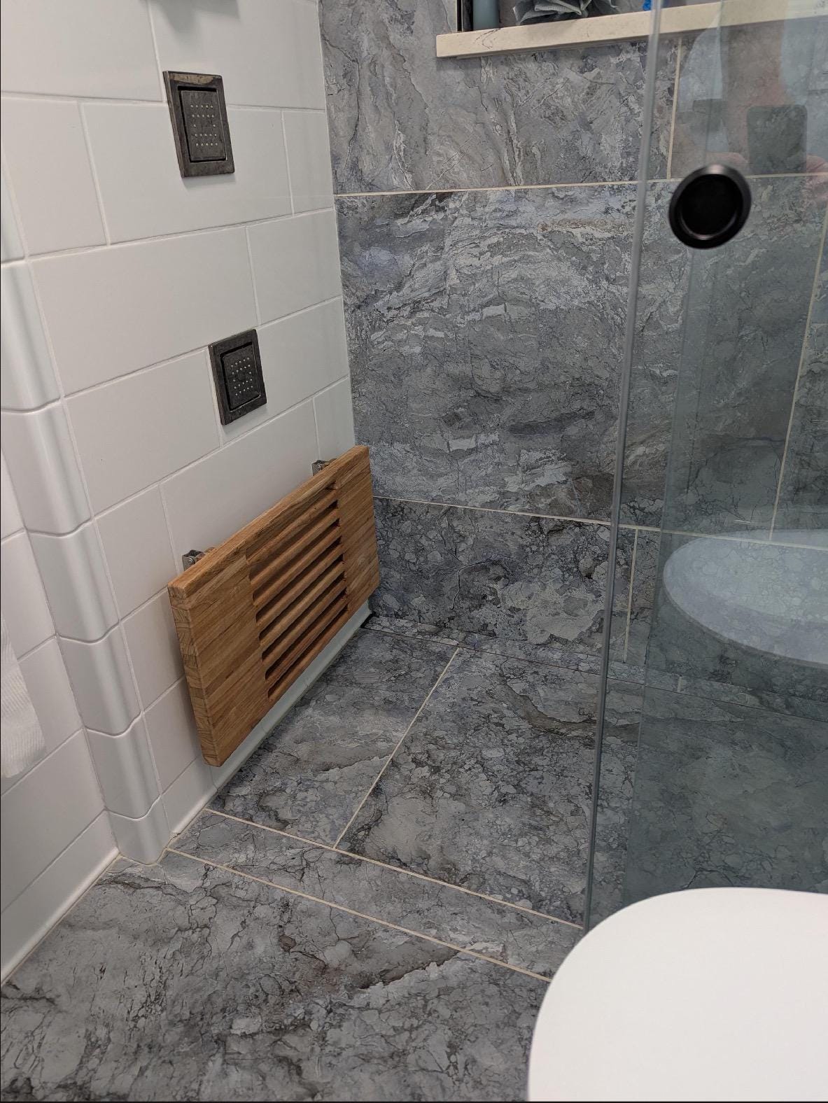 Slatted teak wall-mount bench with drainage gaps between boards against wall