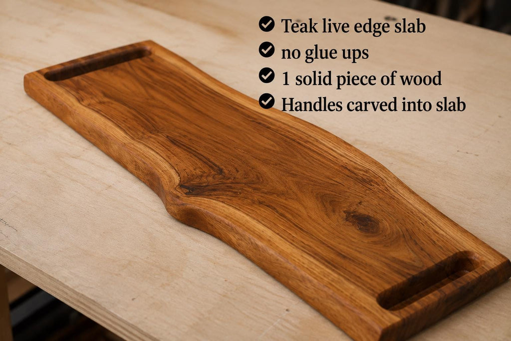 A teak live edge wood serving slab with integrated handles, displayed on a light wood workbench with a text overlay detailing its features.