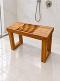 A Freestanding Teak Shower bench in a white tiled shower