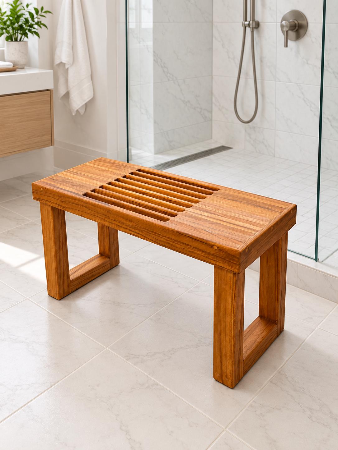 A Freestanding Teak Shower bench in a white tiled Bathroom with a green plant in the top left of the photo
